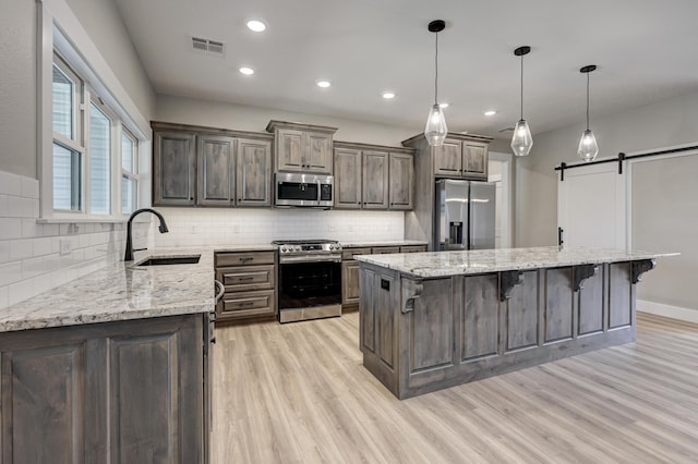 kitchen with sink, a barn door, a kitchen island, stainless steel appliances, and a breakfast bar area