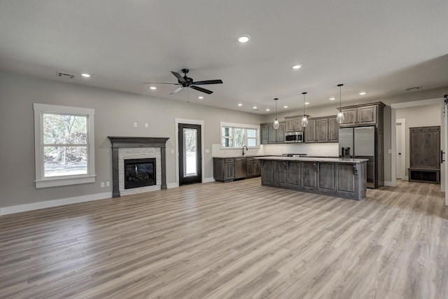 living room with a fireplace, light wood-type flooring, and ceiling fan