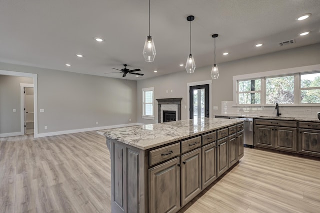 kitchen featuring light stone countertops, light hardwood / wood-style flooring, plenty of natural light, and a kitchen island