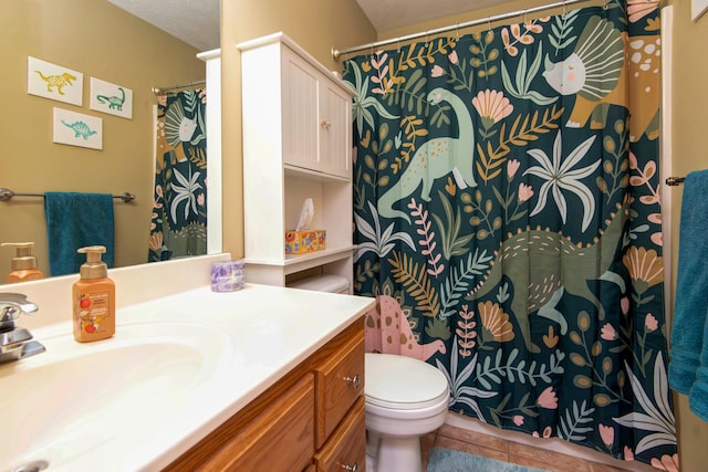 bathroom featuring tile patterned flooring, vanity, a textured ceiling, and toilet