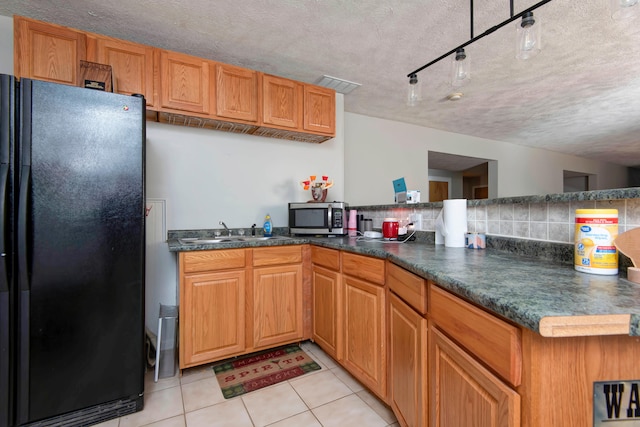 kitchen featuring light tile patterned floors, kitchen peninsula, a textured ceiling, and black refrigerator