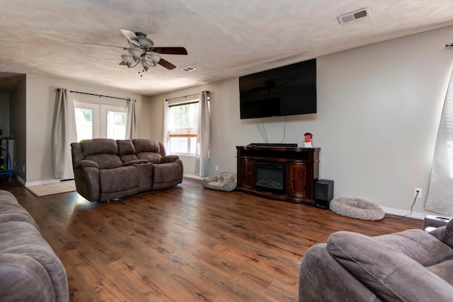 living room featuring hardwood / wood-style floors, ceiling fan, and a textured ceiling