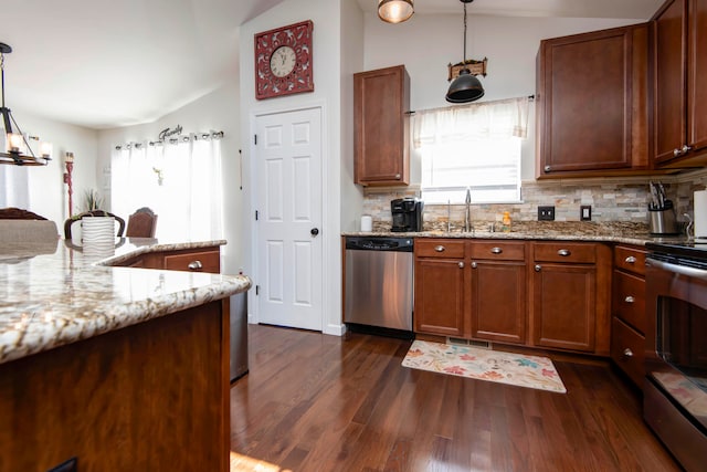 kitchen with appliances with stainless steel finishes, dark wood-type flooring, sink, pendant lighting, and lofted ceiling