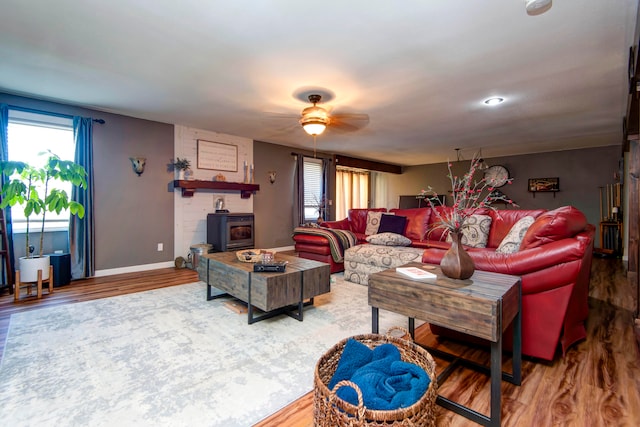 living room with a wood stove, ceiling fan, and hardwood / wood-style floors