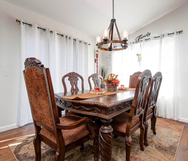 dining area with hardwood / wood-style floors and an inviting chandelier