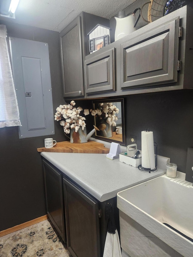 kitchen featuring electric panel, sink, and a textured ceiling