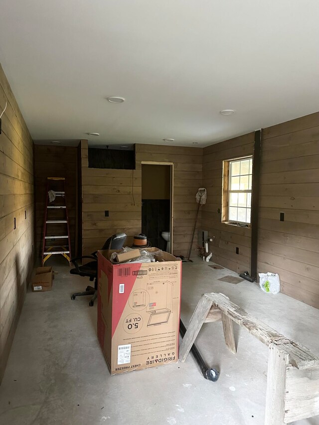 misc room featuring wood walls and concrete floors