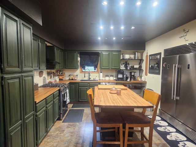 kitchen with green cabinets, wooden counters, appliances with stainless steel finishes, and sink