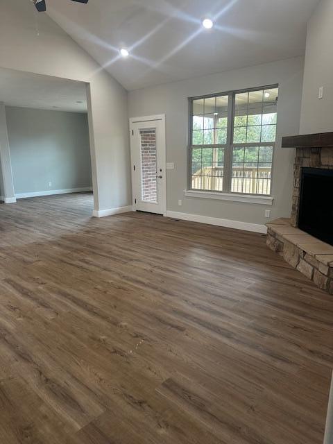 unfurnished living room featuring vaulted ceiling, dark hardwood / wood-style floors, and a fireplace