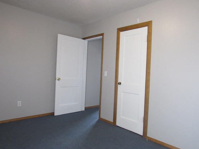 unfurnished room with dark colored carpet and a textured ceiling