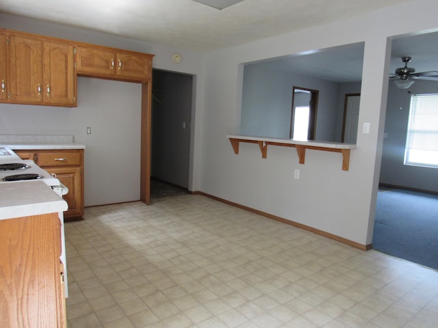 kitchen with kitchen peninsula, ceiling fan, and a breakfast bar