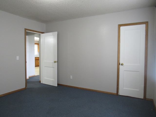 empty room featuring dark carpet and a textured ceiling