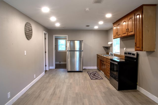 kitchen featuring a sink, baseboards, range with electric stovetop, and freestanding refrigerator