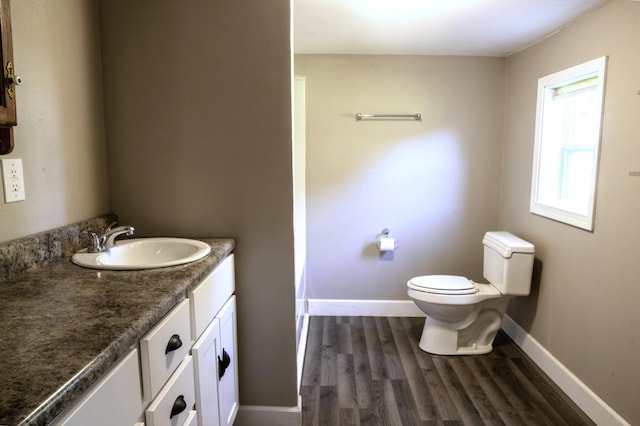 bathroom featuring toilet, vanity, wood finished floors, and baseboards