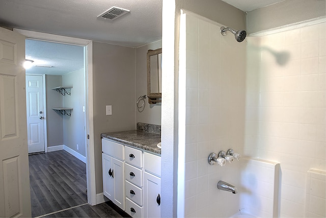 full bathroom featuring wood finished floors, shower / bathtub combination, visible vents, and vanity