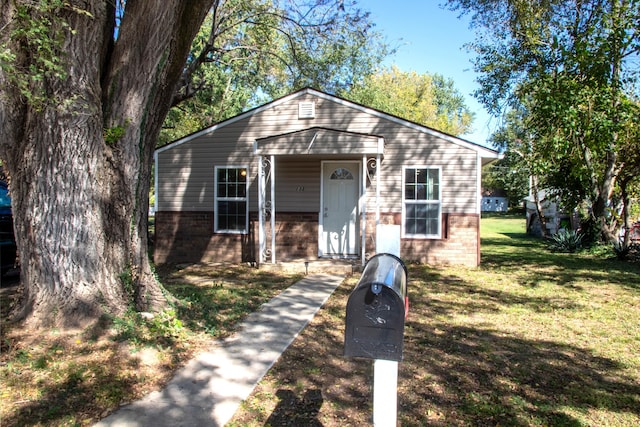 bungalow featuring brick siding and a front yard