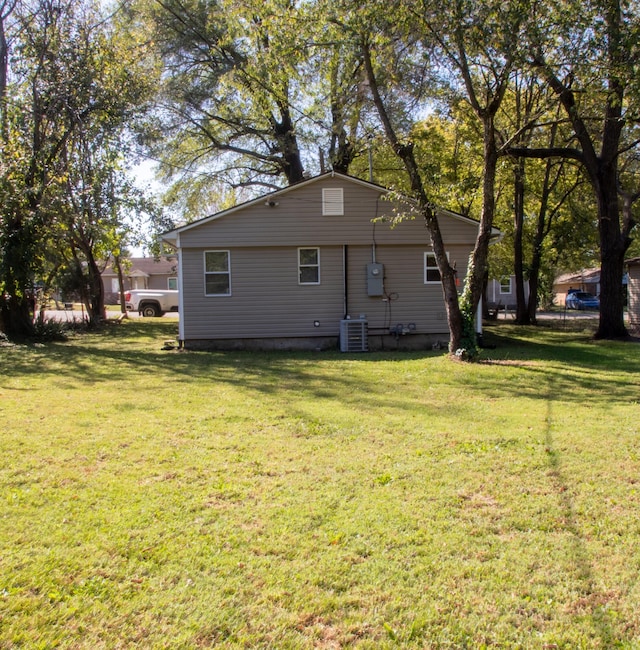 rear view of house with a lawn and cooling unit