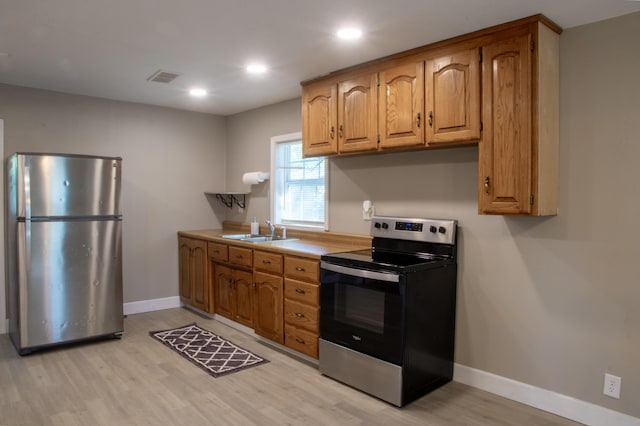 kitchen featuring a sink, stainless steel appliances, light wood finished floors, baseboards, and visible vents