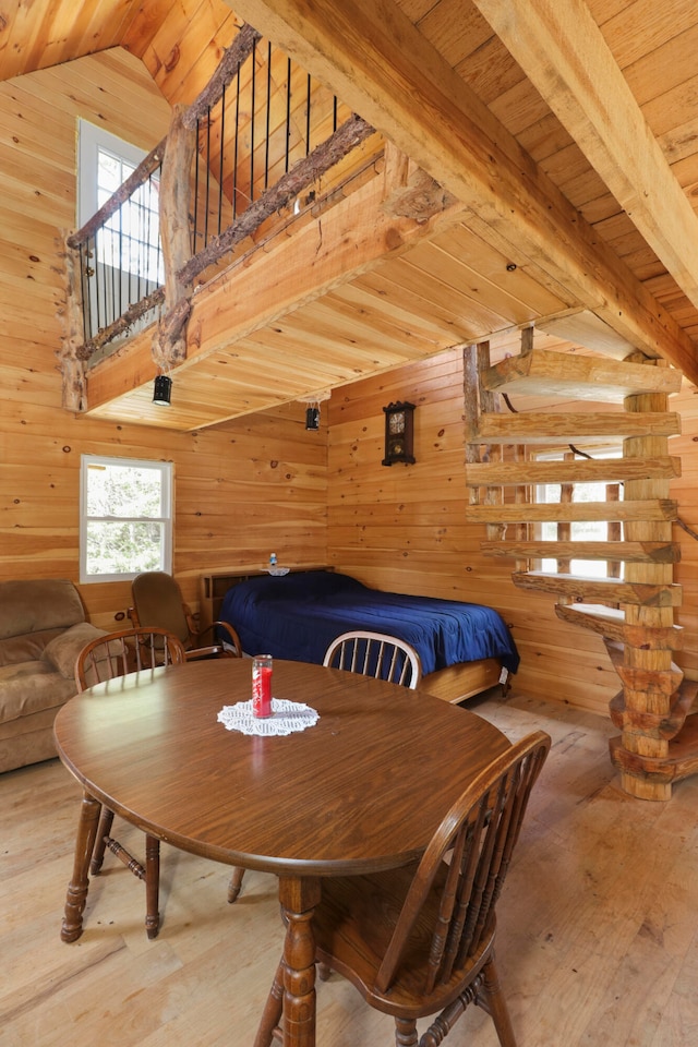 dining space with wood walls, wood-type flooring, wood ceiling, and lofted ceiling with beams