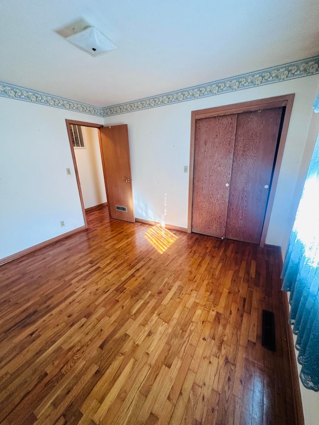 unfurnished bedroom featuring a closet and hardwood / wood-style flooring