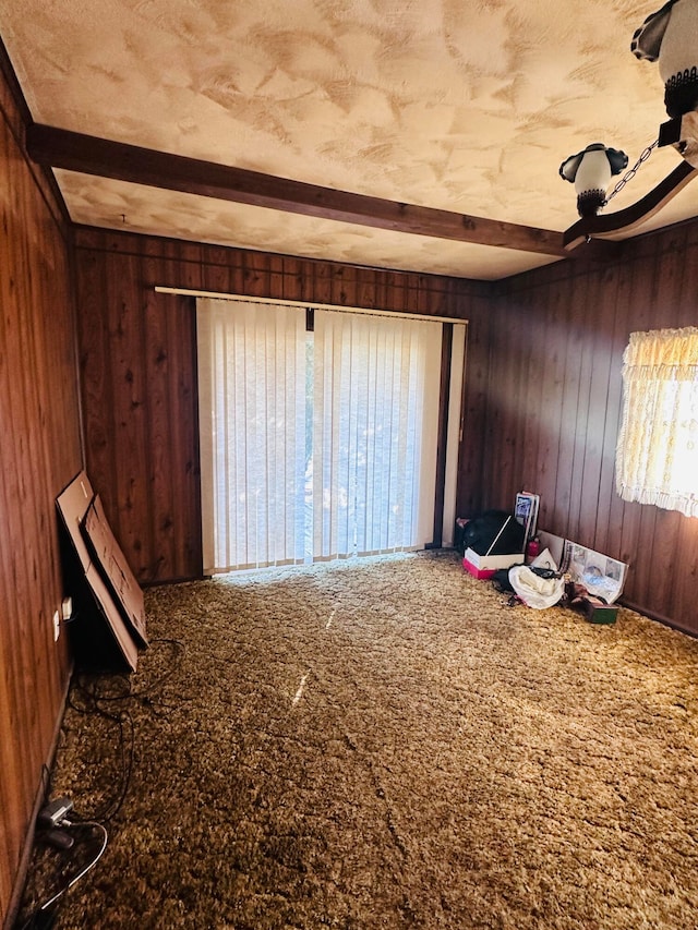 misc room featuring carpet floors, wooden walls, and beamed ceiling