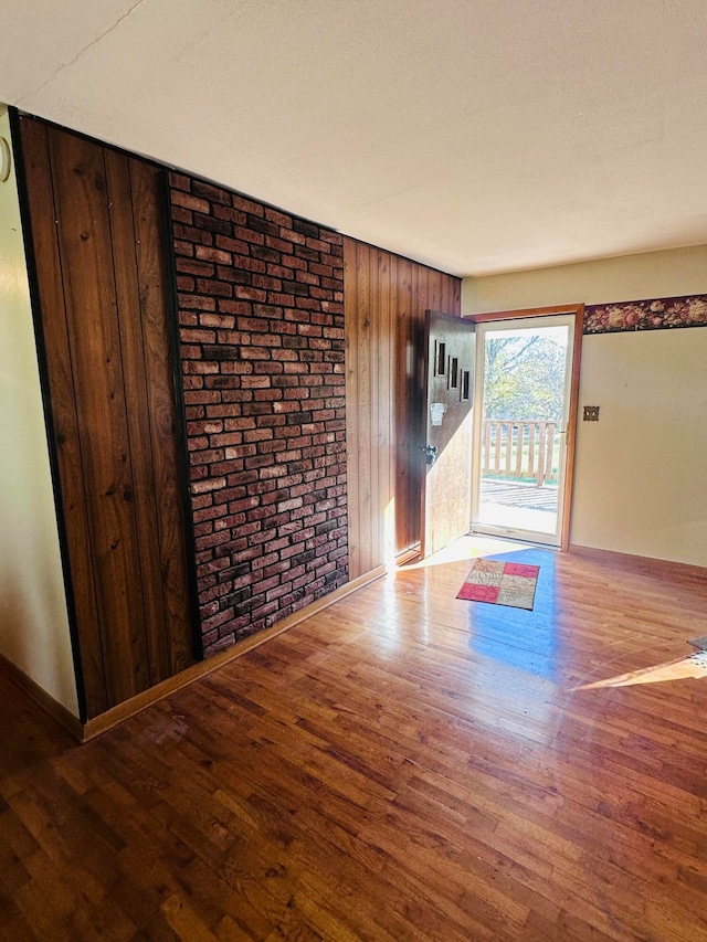 foyer entrance featuring wood walls, wood-type flooring, and brick wall