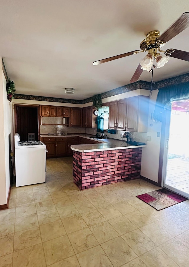 kitchen with ceiling fan, white range, kitchen peninsula, and tasteful backsplash