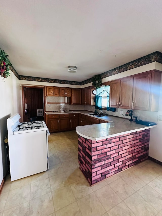 kitchen with kitchen peninsula, white gas stove, light tile patterned floors, and sink