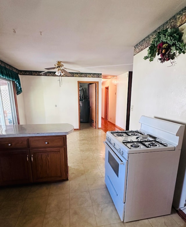 kitchen featuring dark brown cabinets, gas water heater, white range with gas cooktop, and ceiling fan