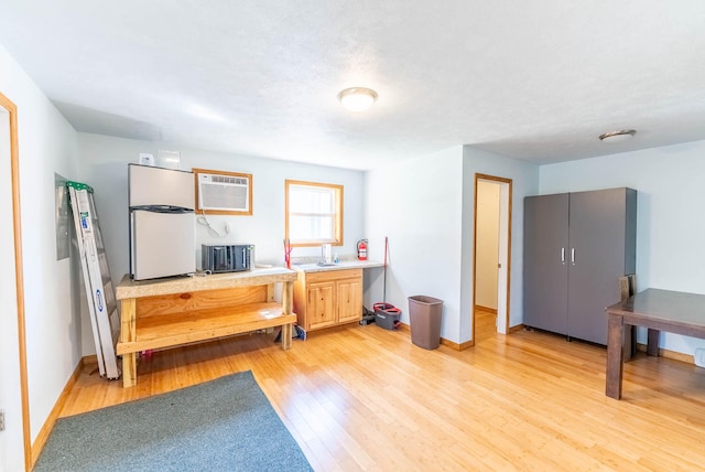 interior space with a wall mounted air conditioner and light hardwood / wood-style flooring