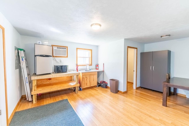 interior space with light wood finished floors, baseboards, and a wall unit AC