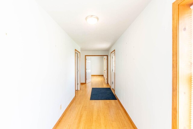 hall featuring light wood-style floors and baseboards
