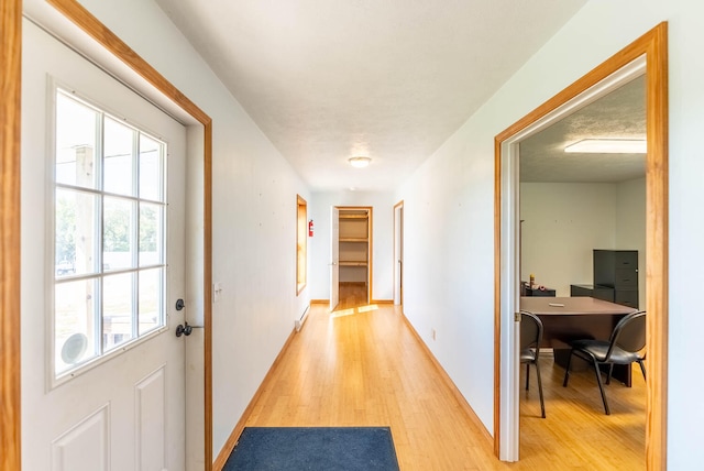 corridor featuring a textured ceiling and light hardwood / wood-style flooring