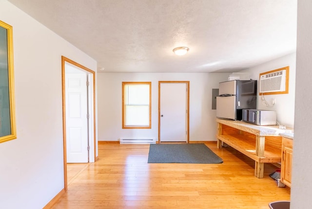 foyer featuring a baseboard radiator, light wood-style floors, a wall mounted air conditioner, and baseboards