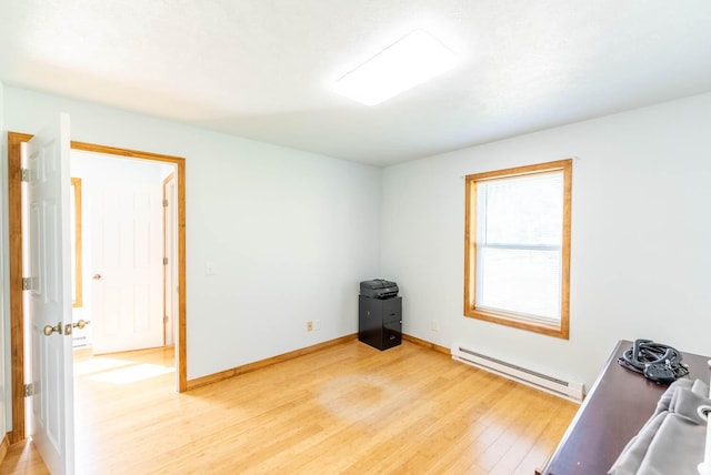 empty room with baseboards, light wood-style floors, and a baseboard radiator