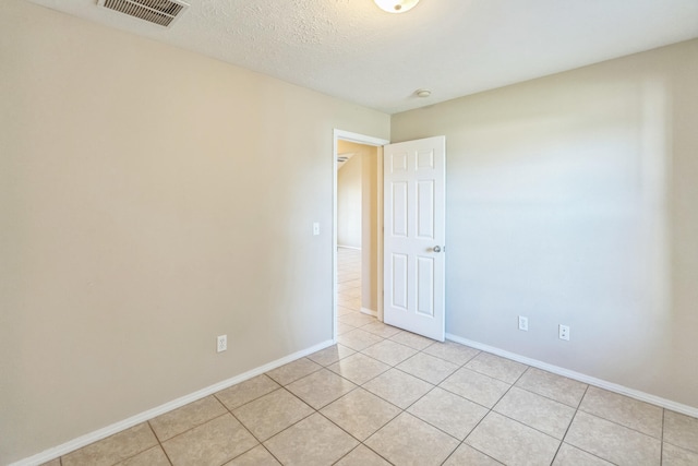 unfurnished room with light tile patterned floors and a textured ceiling