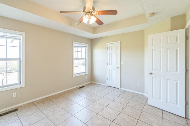 unfurnished bedroom featuring light tile patterned flooring, ceiling fan, and a raised ceiling