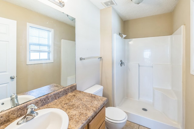 bathroom featuring vanity, a textured ceiling, a shower, tile patterned floors, and toilet