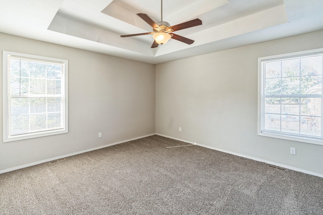 carpeted empty room with ceiling fan and a tray ceiling