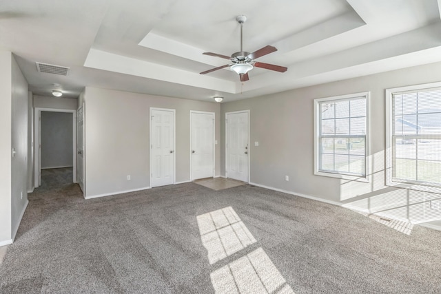 interior space with carpet floors, multiple closets, a tray ceiling, and ceiling fan