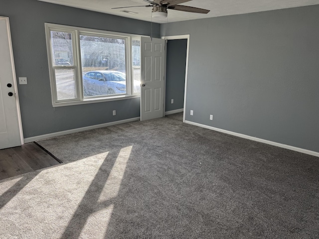 spare room with dark colored carpet and ceiling fan