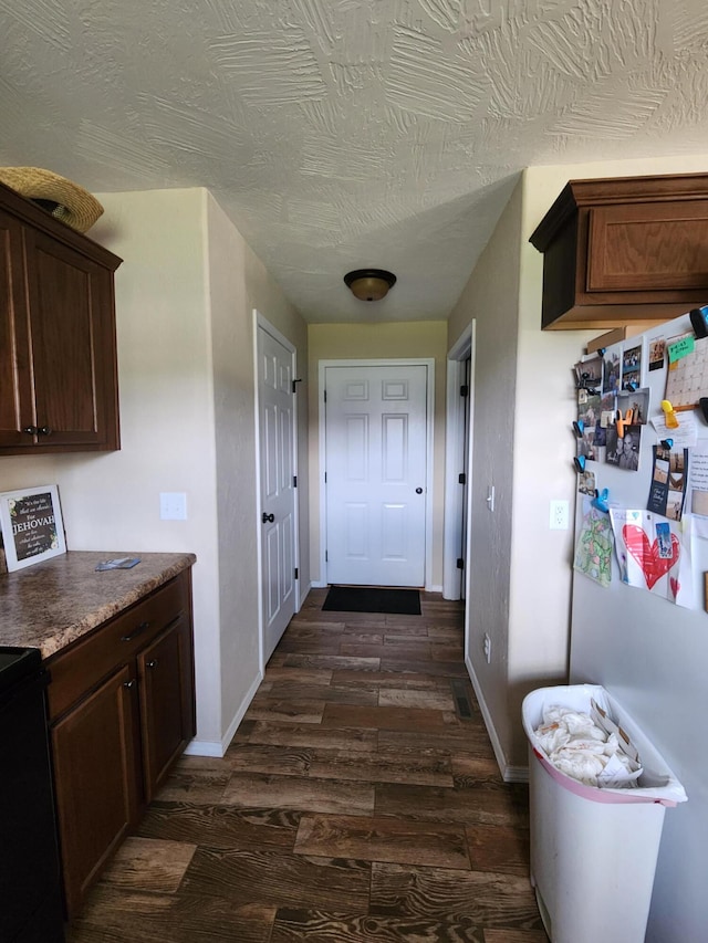 corridor with a textured ceiling and dark hardwood / wood-style flooring