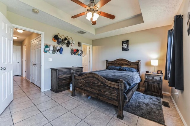 bedroom featuring a raised ceiling, light tile patterned floors, and ceiling fan