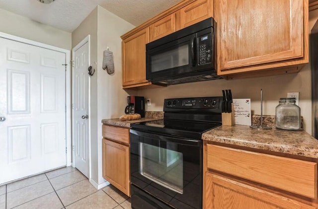 kitchen featuring light tile patterned flooring, stone counters, a textured ceiling, and black appliances