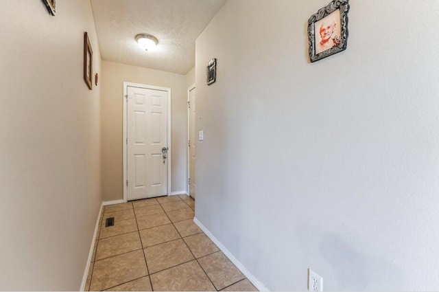 hall featuring light tile patterned floors and a textured ceiling