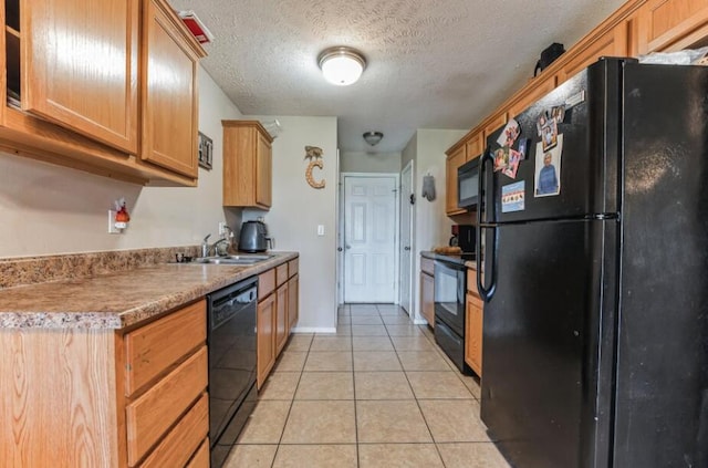 kitchen featuring black appliances, sink, light tile patterned floors, and a textured ceiling