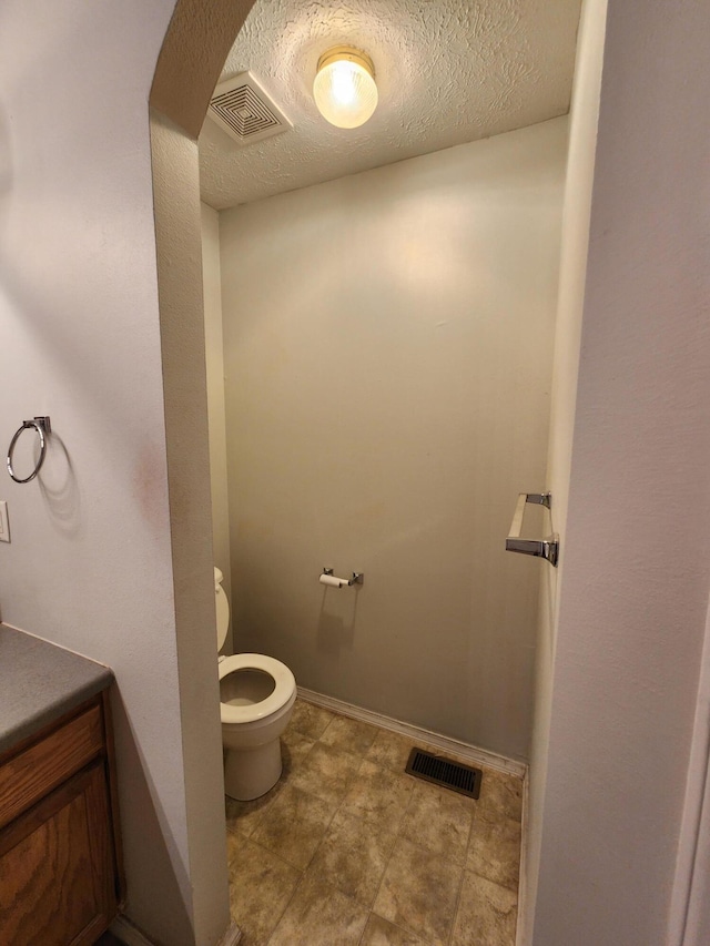 bathroom with vanity, toilet, and a textured ceiling