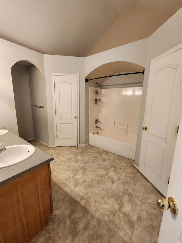 full bath featuring a sink, double vanity,  shower combination, baseboards, and lofted ceiling