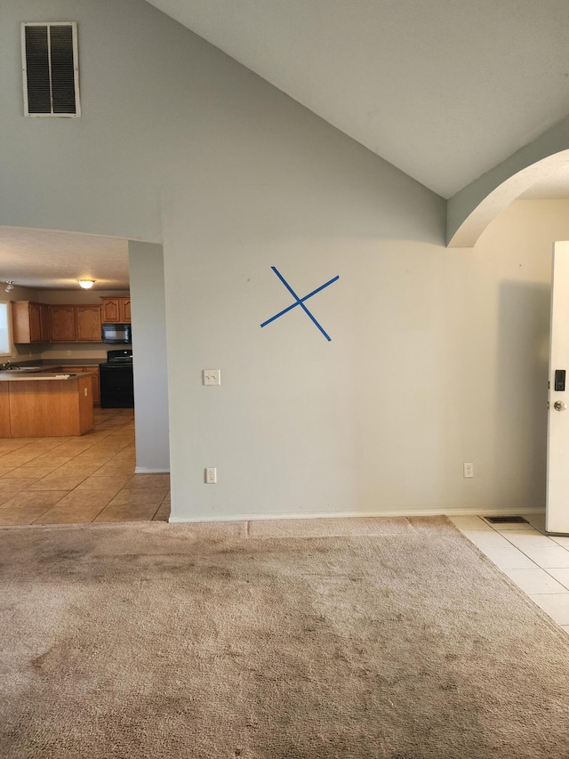 unfurnished living room with light carpet, arched walkways, visible vents, high vaulted ceiling, and light tile patterned floors