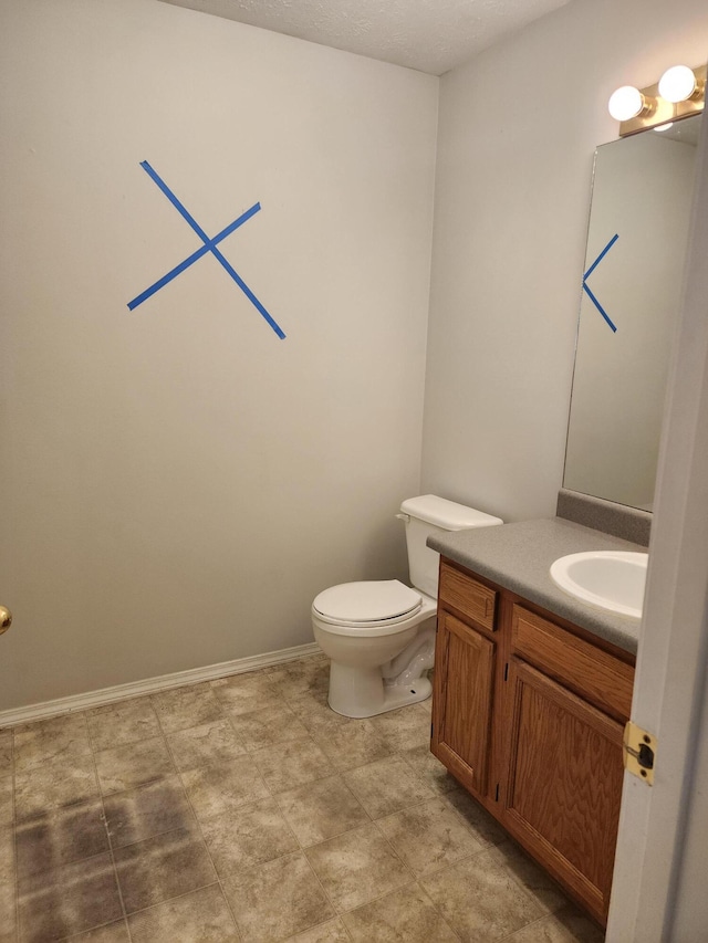 bathroom with toilet, vanity, and baseboards